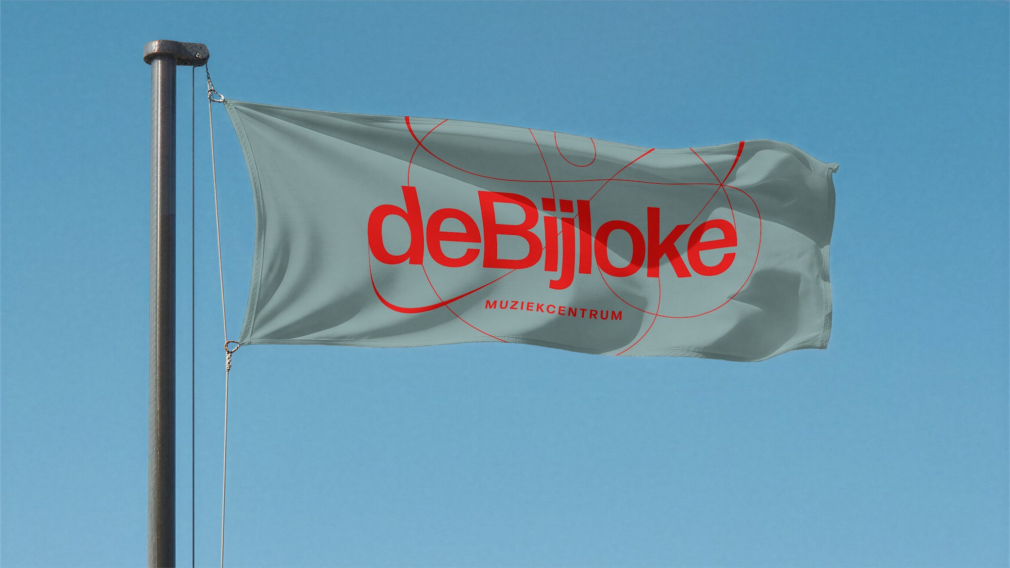 De Bijloke wordmark in red on a sage-green flag