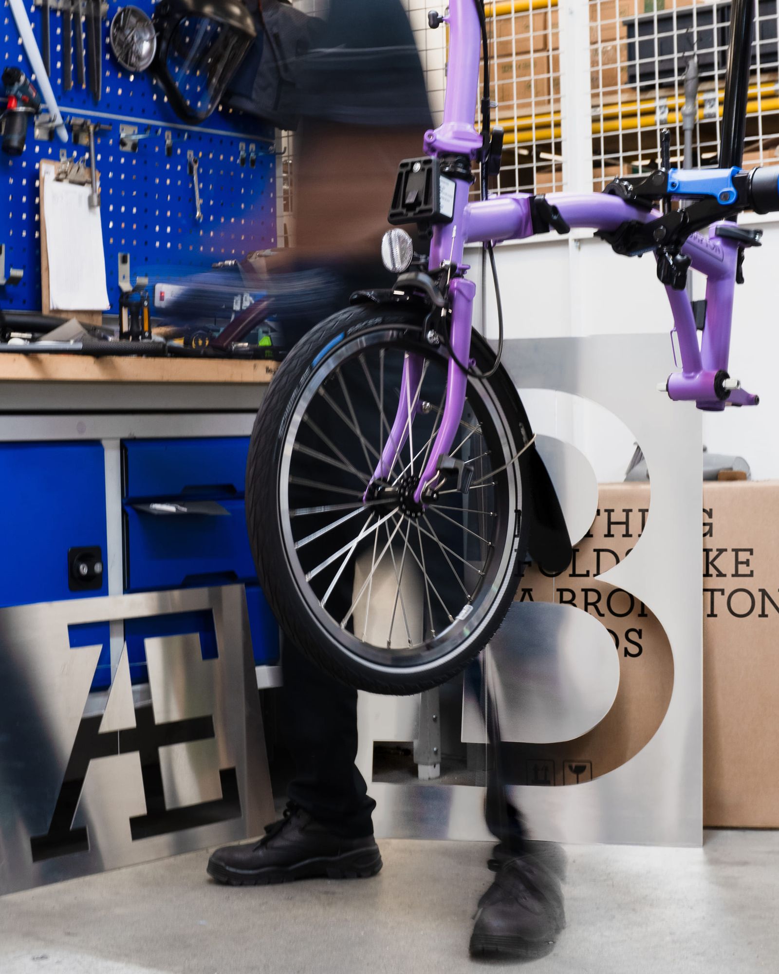 Brompton global branding purple folding bike on assembly stand