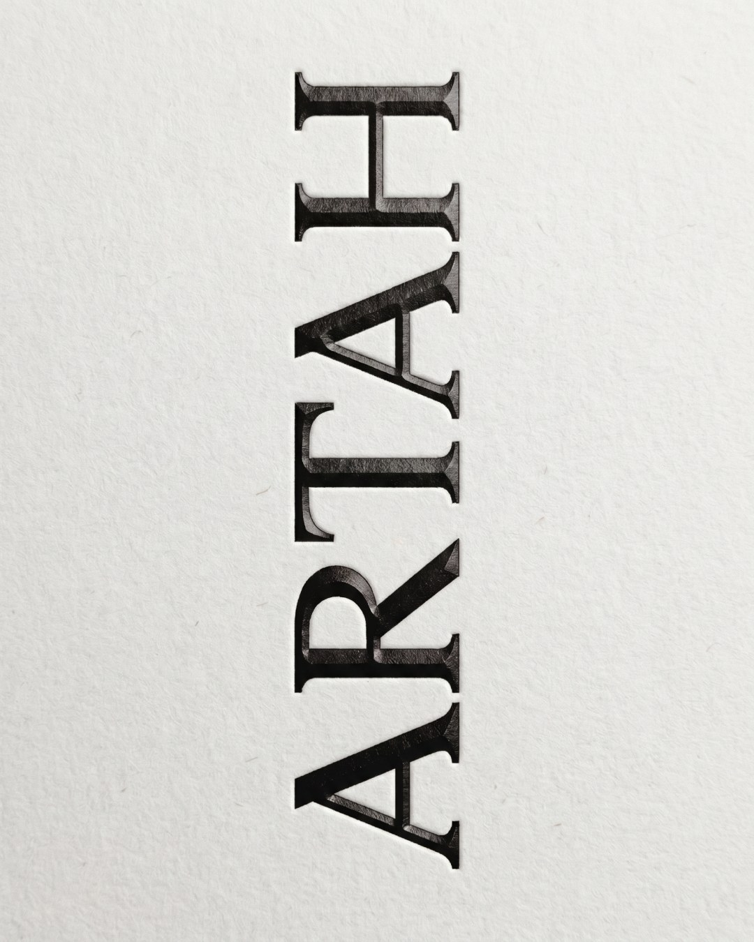 Vertical debossed serif Artah wordmark on textured white paper stock in branding design