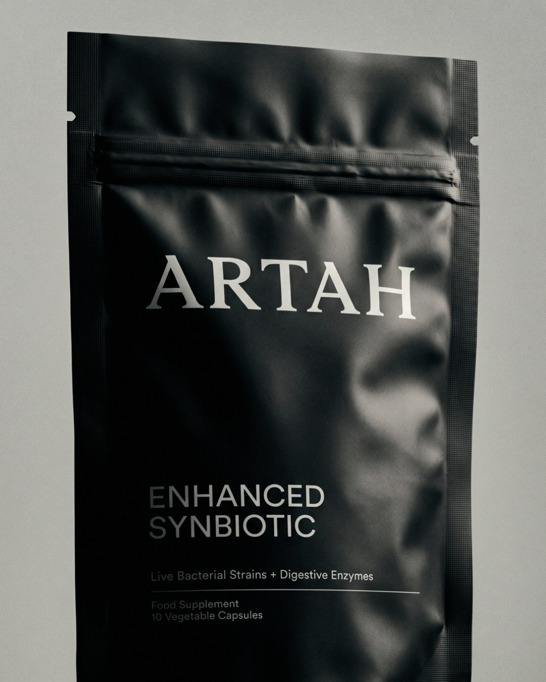 Matte black resealable supplement pouch for Artah Enhanced Synbiotic with serif wordmark in branding design