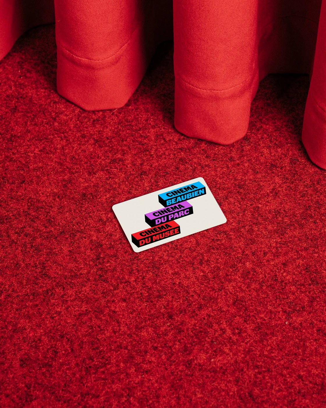 Tactile Cinéma Cinéma membership card on crimson theater carpet and velvet curtain by Deux Huit Huit