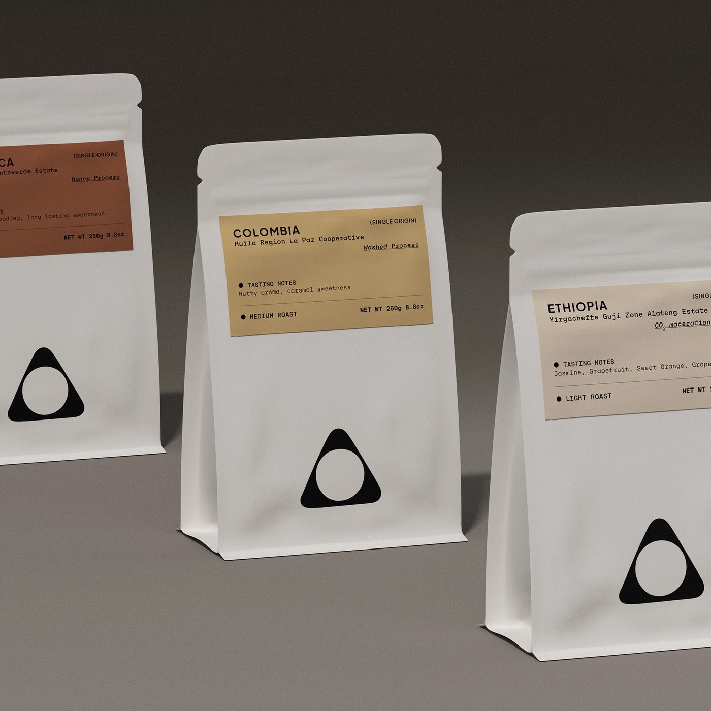 Trio of matte white stand-up coffee pouches with origin label system in Desert Coffee branding