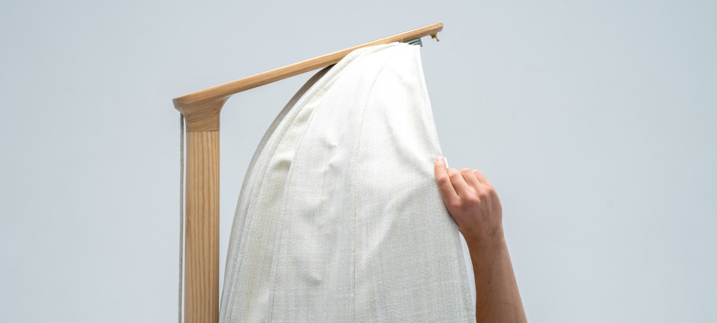 Detail of hand adjusting the fabric acoustic cocoon dome on Shanti chair industrial design