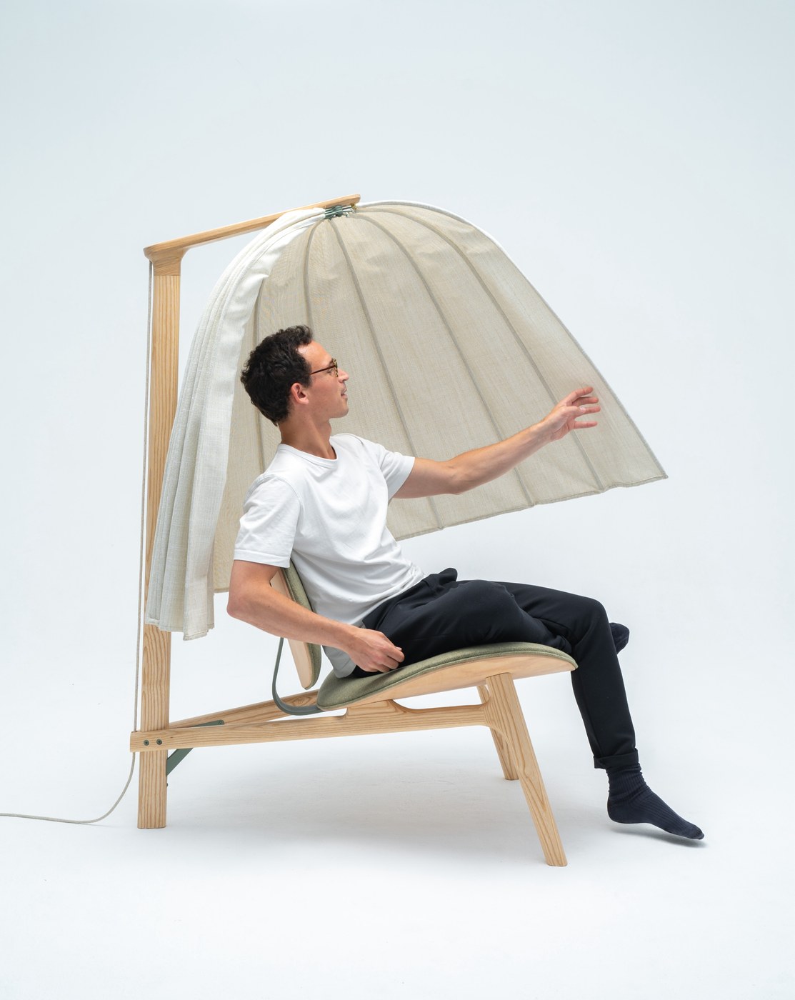 User seated cross-legged inside Shanti meditation chair acoustic cocoon industrial design