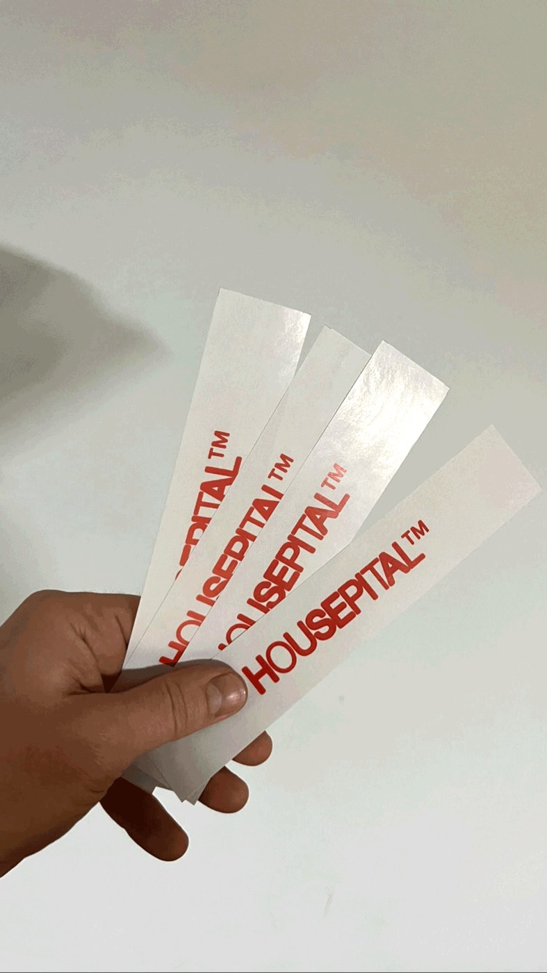 Physical admission wristbands printed in red ink with Housepital branding logo