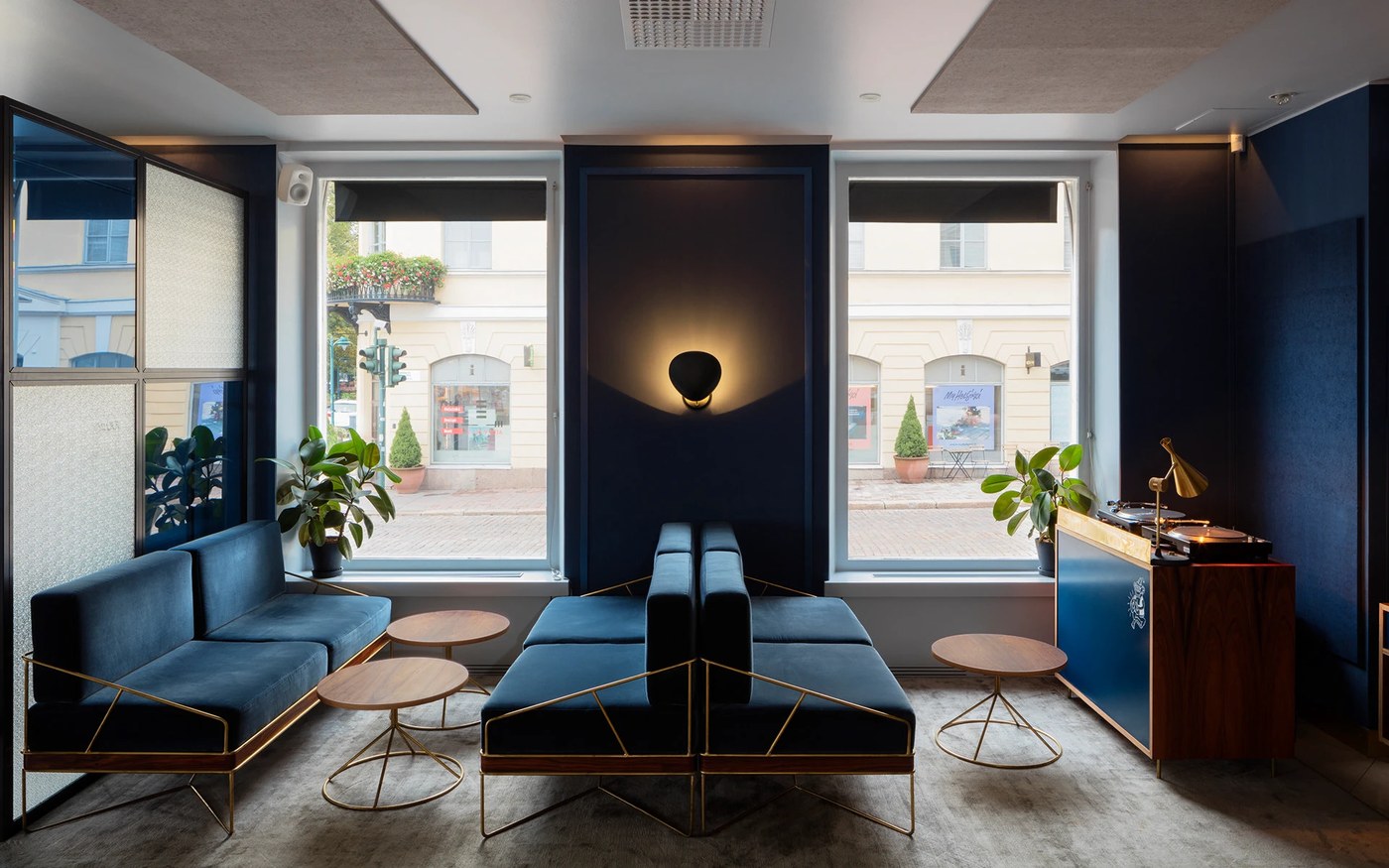 Cocktail lounge interior with navy velvet daybeds, brass geometric frames, and custom DJ console in Roster branding design